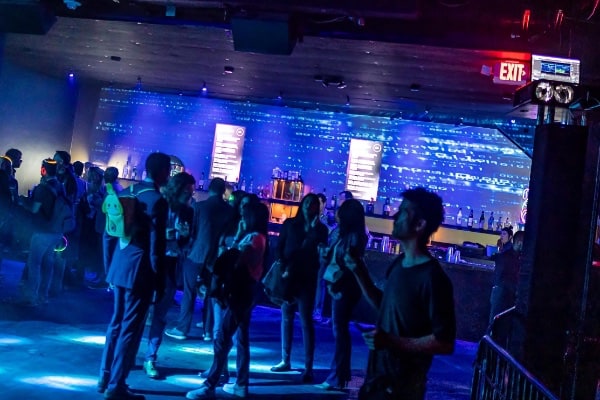 a group of people standing in a room with a large screen